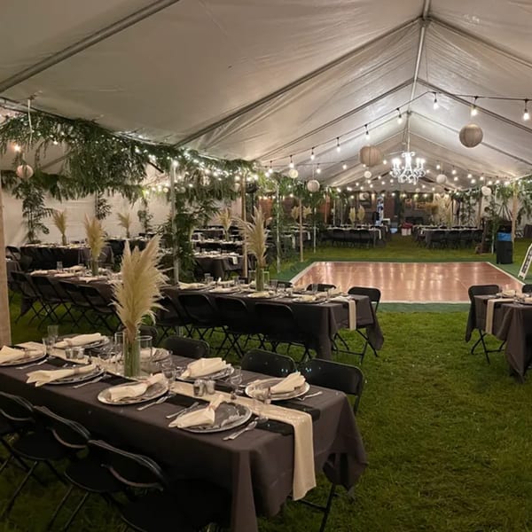 An outdoor tented event space with dining tables, a dance floor, and string lights at Rendezvous Bar & Grill.